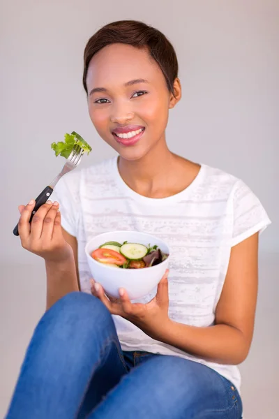 Donna seduta sul pavimento e mangiare insalata — Foto Stock