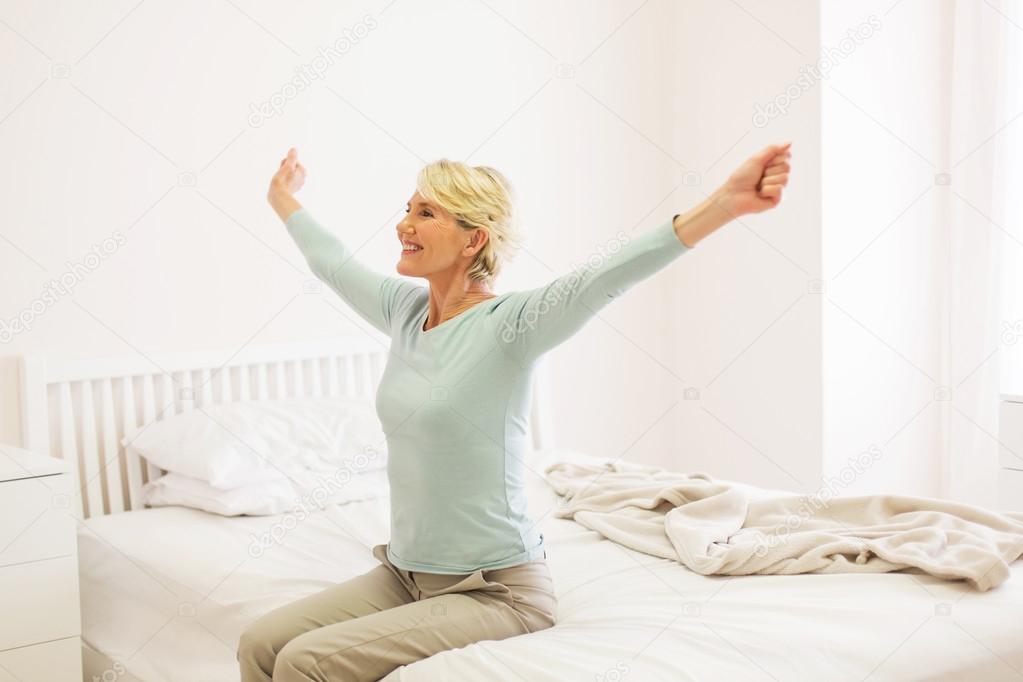 woman sitting on bed and stretching