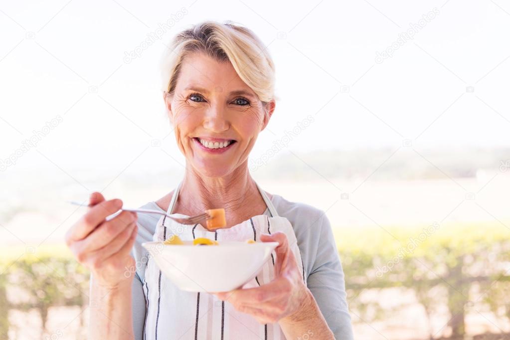mature woman eating fruit salad
