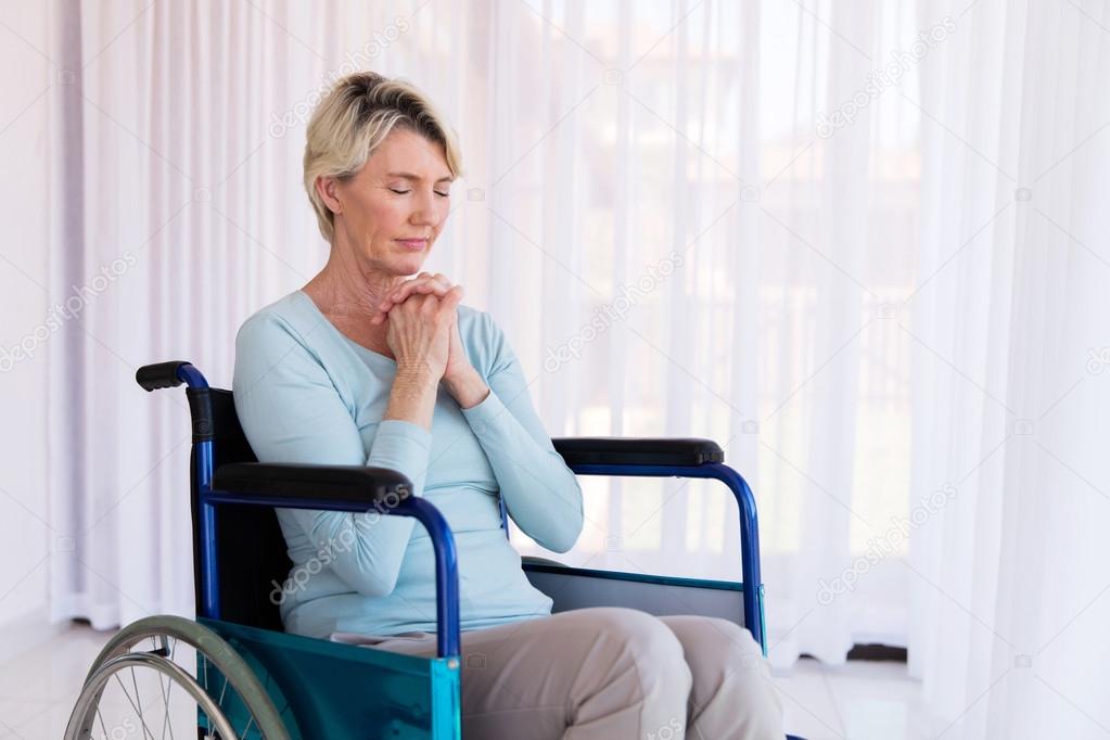 woman sitting on wheelchair and praying