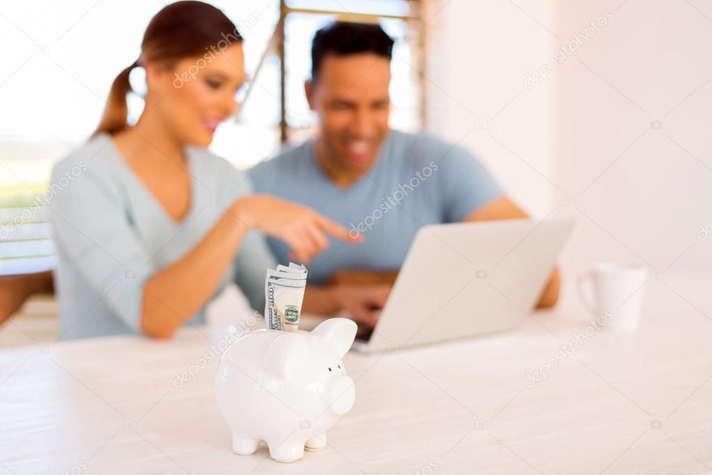 piggybank with couple using laptop