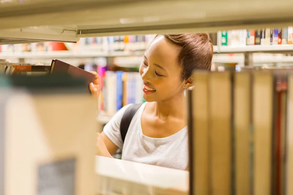 Estudante na biblioteca à procura de livros — Fotografia de Stock