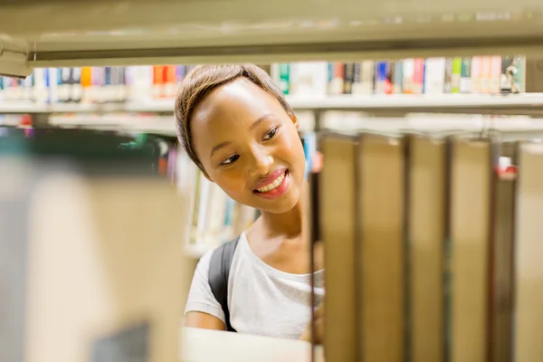 Studentin in Bibliothek sucht nach Büchern — Stockfoto