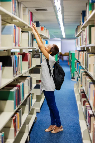 Student hledá knihu v knihovně — Stock fotografie