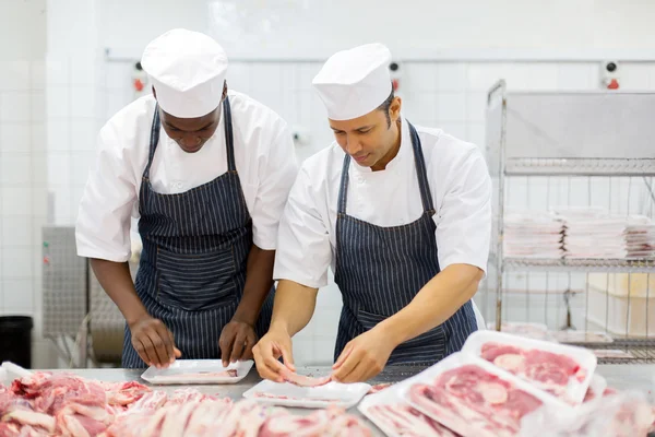 Açougueiros embalando pedaços de carne — Fotografia de Stock