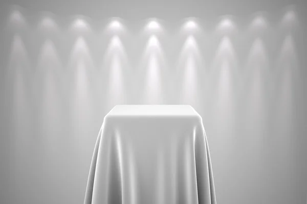 Pedestal com pano de seda branco e luz spot — Fotografia de Stock