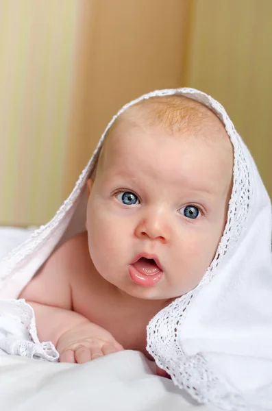 O bebé está escondido debaixo do cobertor branco. — Fotografia de Stock