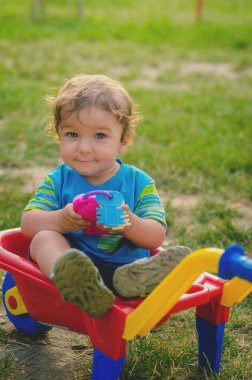 Renkli çocuk plastik yapı el arabası ile oynarken küçük çocuk yürümeye başlayan çocuk