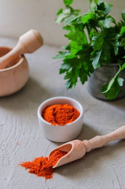 Tabakta baharatlı kırmızı biber ve gri arka planda kaşığı ölçmek. Ev mutfağı.