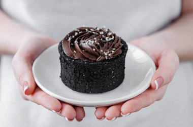 Kadın elinde bir tabak çikolatalı pasta tutuyor. Ev yapımı tatlılar.