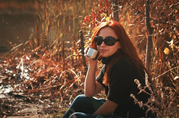 Eine Frau trinkt Tee aus einer Thermoskanne, um sich warm zu halten — Stockfoto