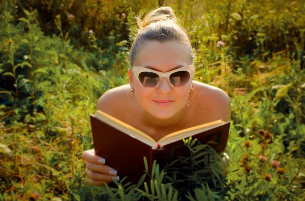 Mulher bonita deitada na grama e lendo um livro — Fotografia de Stock