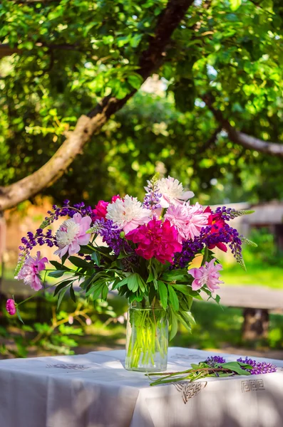 Hermoso ramo de peonías y altramuz sobre la mesa en el gree —  Fotos de Stock