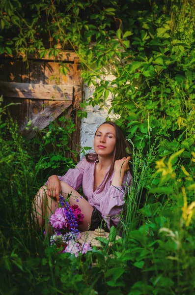 Mulher macia descansando em moitas gramíneas com um belo buquê — Fotografia de Stock