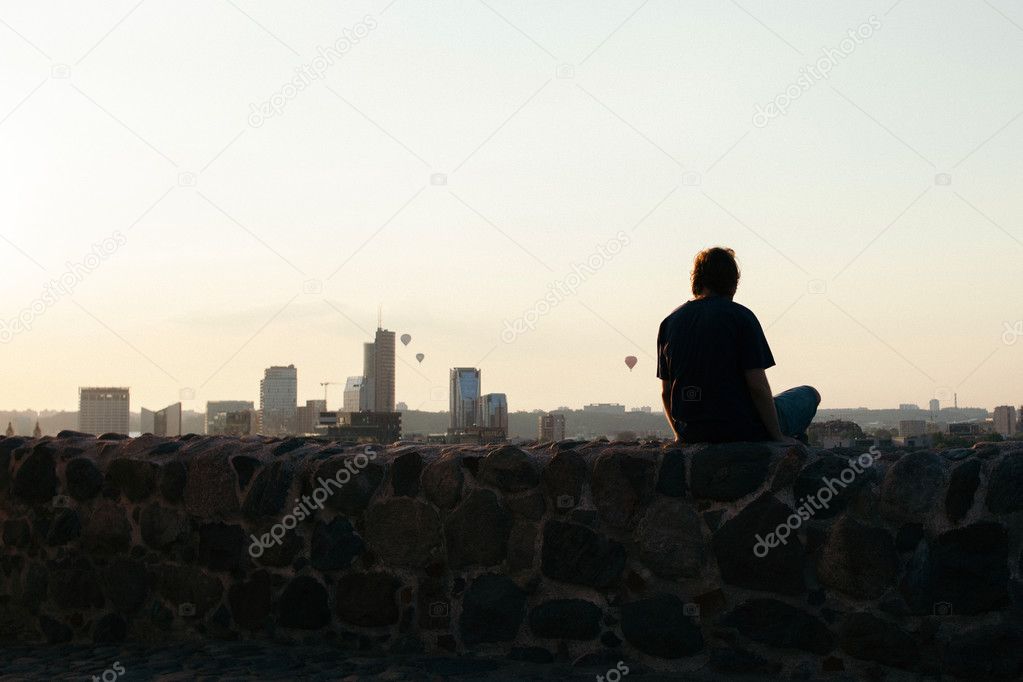 Young man looking over the city during sunset