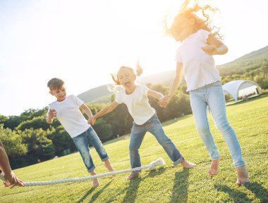 Çocuklar parkta römorkör oynuyorlar. Doğada aktif olarak birlikte oynayan bir grup sevimli çocuk. Dışarıda sevimli çocuklar var..