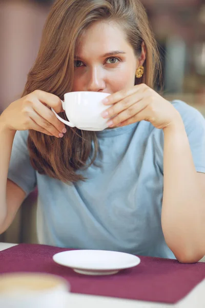 Thoughtful mature woman sits in a cafeteria holding a coffee mug. A middle-aged woman drinks tea while thinking. Relaxing and thinking while drinking coffee. — Stock Photo, Image