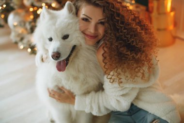 Köpekli güzel bir kadın, şöminenin arka planında ve mumlu bir Noel ağacında.. 