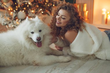 Köpekli güzel bir kadın, şöminenin arka planında ve mumlu bir Noel ağacında.. 