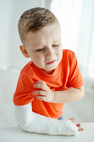 Kleiner Junge in einem Cast.Kind mit gebrochenem Arm. Lustiges Kind nach Unfall. — Stockfoto