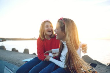 Parkta kaykayla oynayan iki bayan arkadaş. Kaykaylı kızlar. Kahkaha ve eğlence.