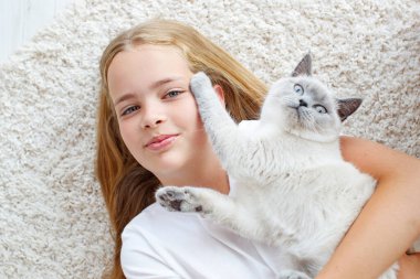 Güzel küçük bir kız yerde tüylü bir kediyle yatıyor. Hayvanlı bir çocuk.. 