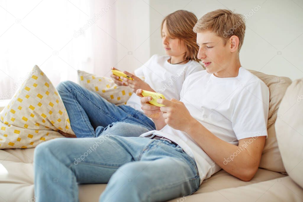 leisure, technology, technology, family and people concept - happy boys and boy with smartphones sending text messages or playing games at home