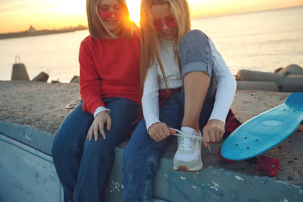 Dos amigas jugando con monopatín en el parque. Chicas con monopatín. Risa y diversión. — Foto de Stock