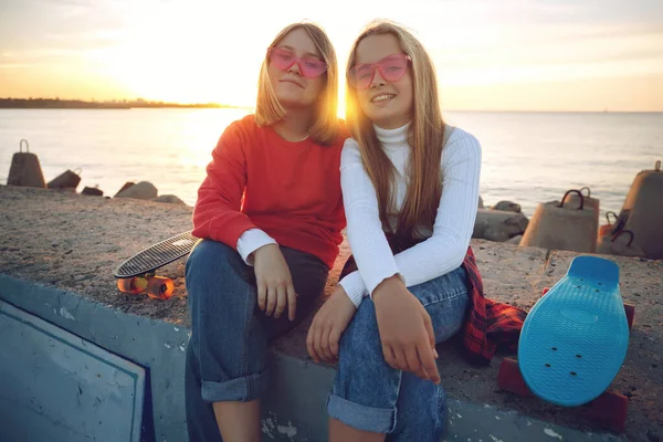 Dos amigas jugando con monopatín en el parque. Chicas con monopatín. Risa y diversión. — Foto de Stock