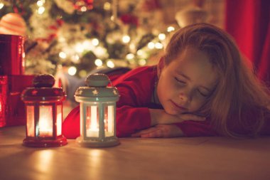 İyi tatiller. Noel ağacının yanında küçük şirin bir çocuk. Kız gülüyor ve Noel 'in tadını çıkarıyor..