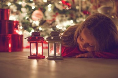 İyi tatiller. Noel ağacının yanında küçük şirin bir çocuk. Kız gülüyor ve Noel 'in tadını çıkarıyor..