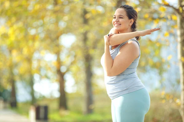 Spor tişörtlü ve taytlı çekici bir kadın spor için şehir parkında spor yapıyor..