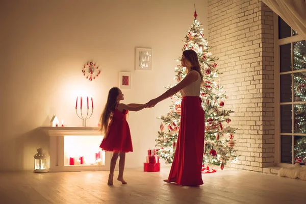 Merry Christmas and Happy Holidays. Mom and daughter with a Christmas tree indoors at night. The evening before Christmas. Portrait of a loving family nearby. — Stock Photo, Image