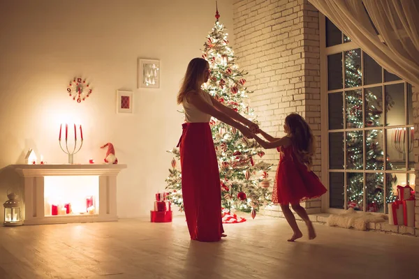 Merry Christmas and Happy Holidays. Mom and daughter with a Christmas tree indoors at night. The evening before Christmas. Portrait of a loving family nearby. — Stock Photo, Image