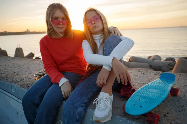 Deux amies qui jouent au skateboard dans le parc. Des filles avec un skateboard. Rire et plaisir. — Photo