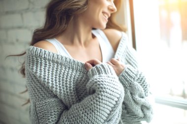 Evde kalın örgü elbiseli güzel bir kadın var. Kadın iç mekan portresi.