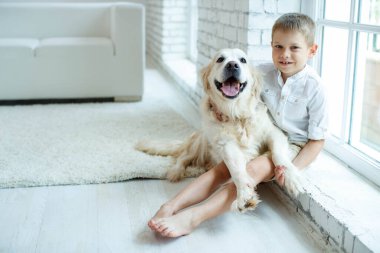 Evde halıda köpeği olan küçük bir çocuk. Arkadaşlık, ilgi, mutluluk, yılın yeni konsepti..