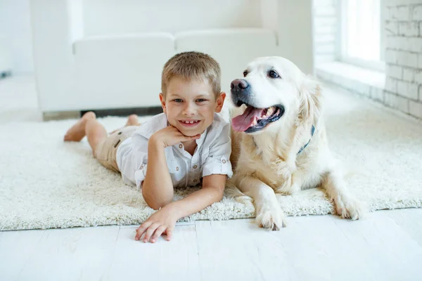 Evde halıda köpeği olan küçük bir çocuk. Arkadaşlık, ilgi, mutluluk, yılın yeni konsepti..