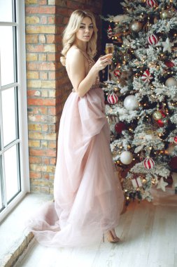 Parti, içkiler, tatiller, insanlar ve kutlama konsepti. Bir bardak köpüklü şarap ve şampanyayla gülümseyen güzel elbiseli kadın..