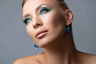 Sarışın, uzun at kuyruklu bir saç stili. Güzellik Moda Kadını Portresi. Makyajlı, küpeli, yüzüklü, poz veren, stüdyo arka planında soyutlanmış güzel bir manken.