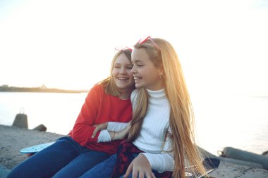 Parkta kaykayla oynayan iki bayan arkadaş. Kaykaylı kızlar. Kahkaha ve eğlence.