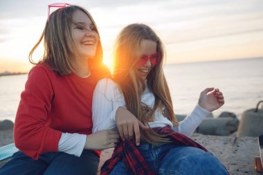 Parkta kaykayla oynayan iki bayan arkadaş. Kaykaylı kızlar. Kahkaha ve eğlence.