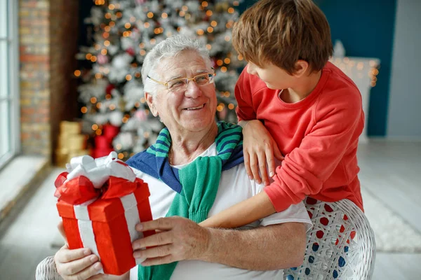 Dedem ve torunlarım Noel için dekore edilmiş bir odada Noel ağacının arka planında. Noel tatili kavramı. kontrastlı fotoğraf.