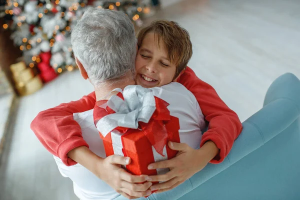 クリスマスのために孫と一緒にいる老人。子供は祖父に休日の贈り物を与える. — ストック写真