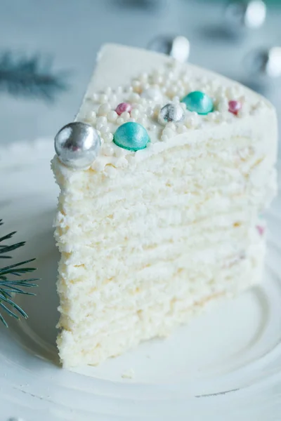 Waniliowe ciasto biszkoptowe ze śmietaną i białą czekoladą. Kawałek ciasta na białym talerzu. Ulubiony deser z okazji imprezy lub urodzin. — Zdjęcie stockowe