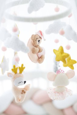 Üstünde bir beşik ve oyuncak var. Çocukların yatağının üzerinde narin bir oyuncak asılı..