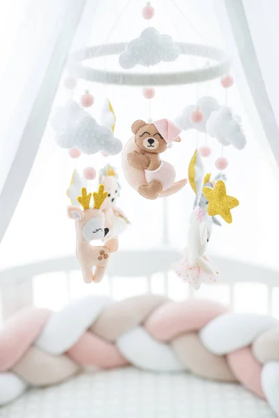 A crib and a toy above it. A delicate toy hangs over the childrens bed.