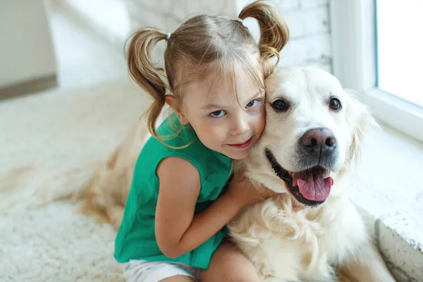 Happy child with a dog. Portrait of a girl with a pet. Labrador Retriever at home. — Stock Photo, Image