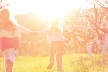 Çocuklar gün ışığında dışarıda. Çocuklar parkta el ele koşarlar.. 