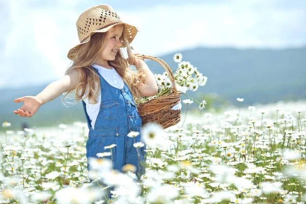 Klein meisje in een veld van bloemen. Het kind heeft plezier in de natuur. — Stockfoto